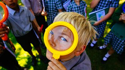 A boy looks through a magnifying glass. Him and his schoolmates have been working with WWF to learn more about nature in their school