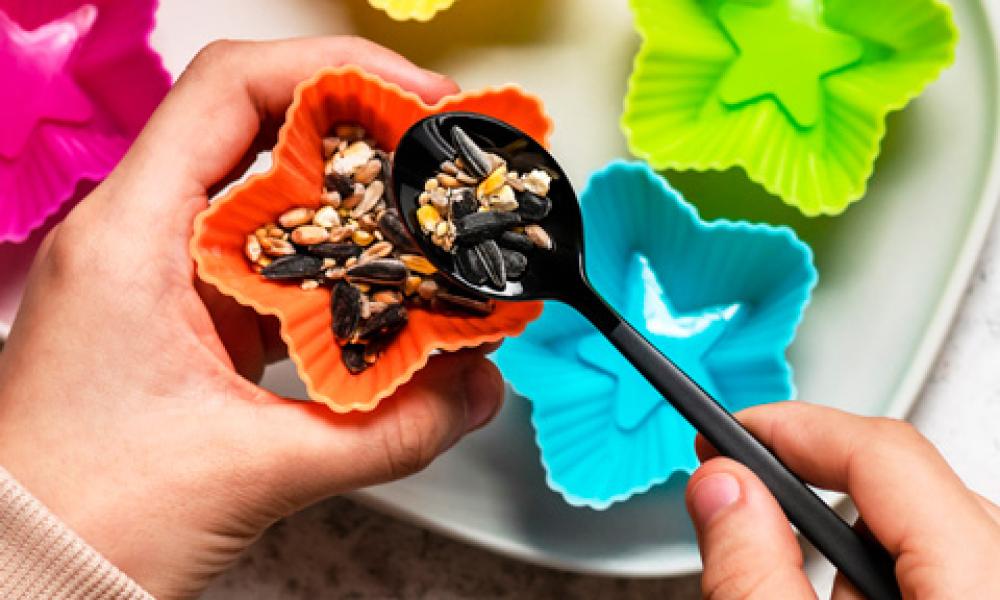 Bird seed being spooned into muffin tin