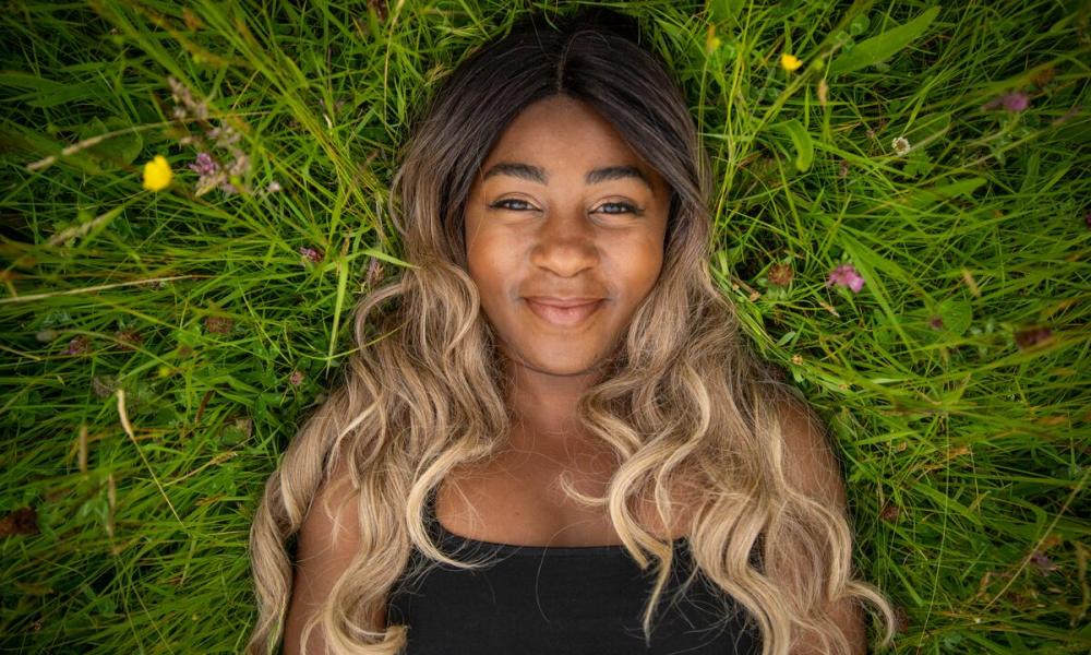 Girl laying in green field looking at camera